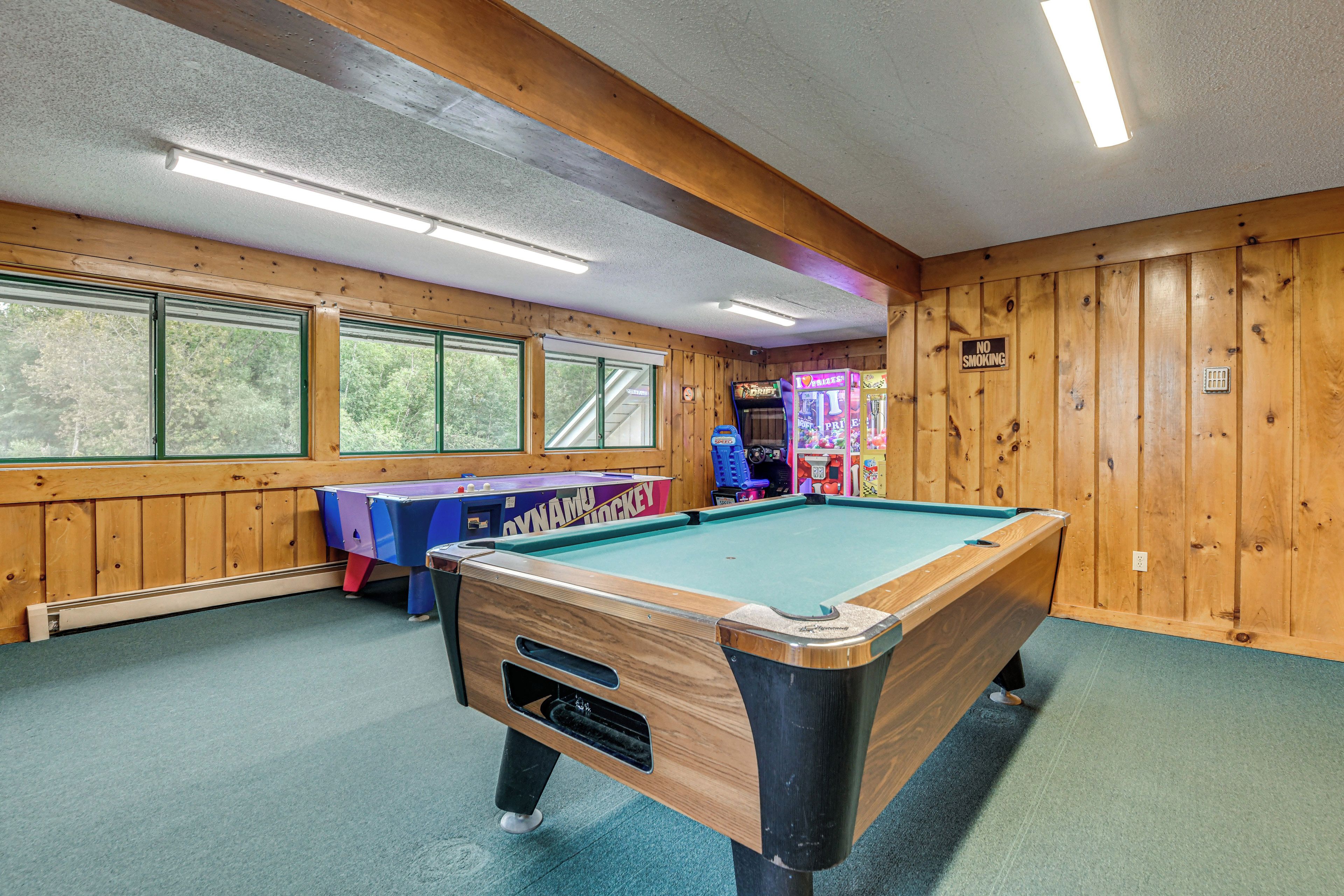 A pool table in a room with wooden walls and large windows.
