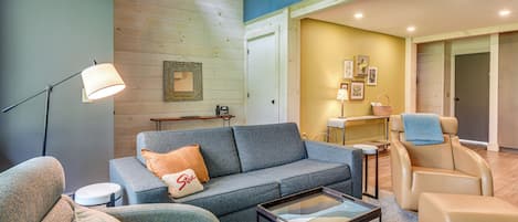 A modern living room with a grey sofa, a small round table, and a floor lamp.