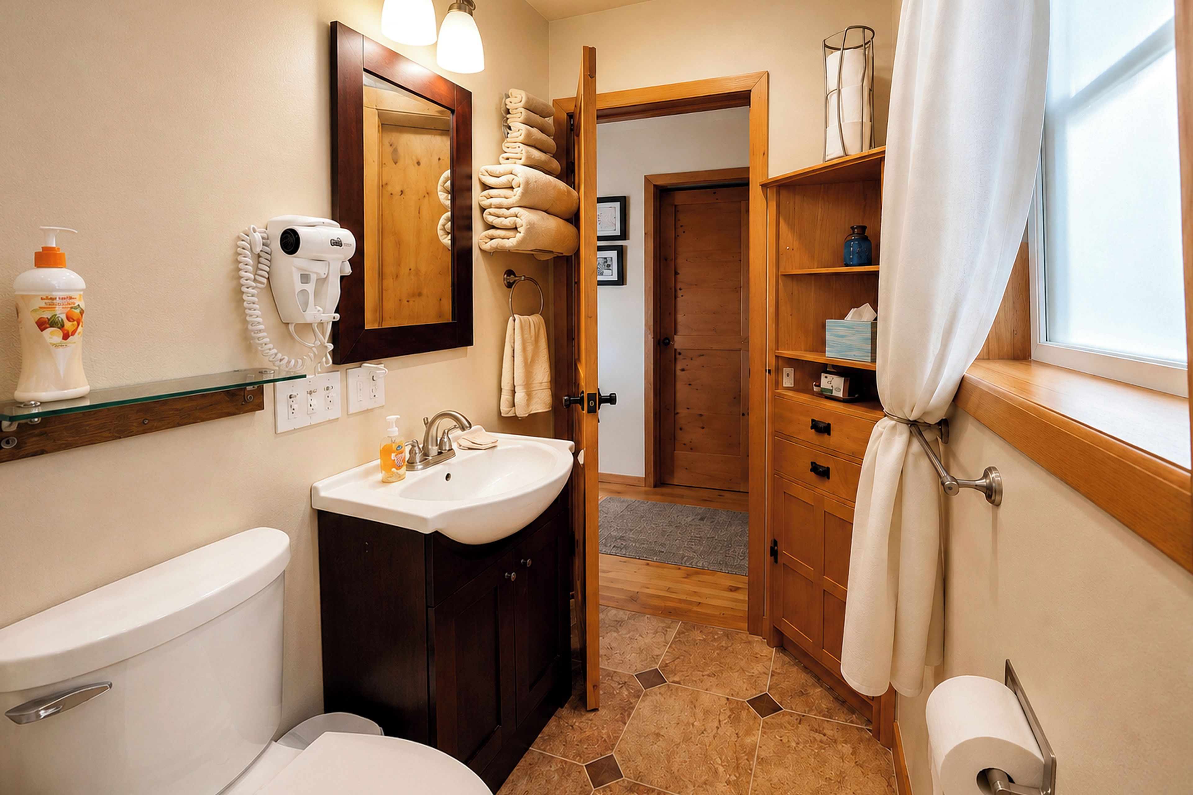 A bathroom with a toilet, sink, and mirror. There are towels and a hairdryer on the wall.