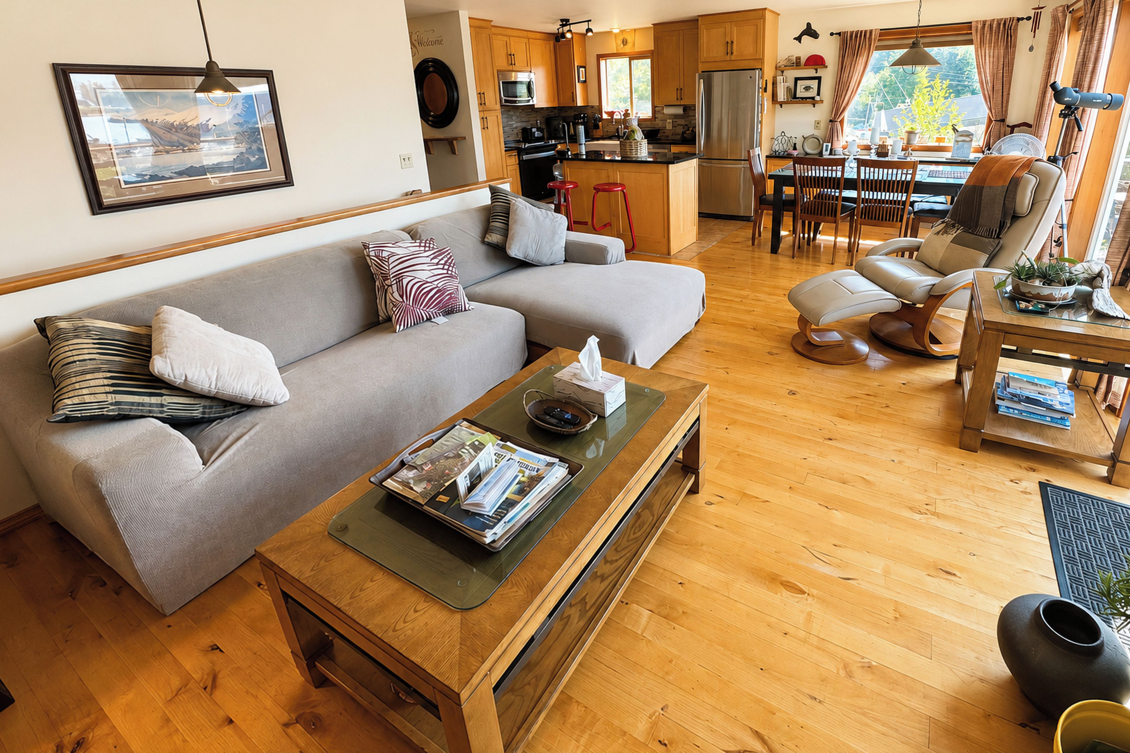 A modern living room with a grey sofa, a wooden coffee table, and a dining area with a table and chairs.