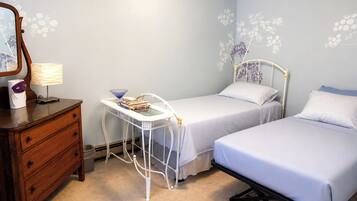 A bedroom with two beds, a bedside table, a dresser, and a mirror.