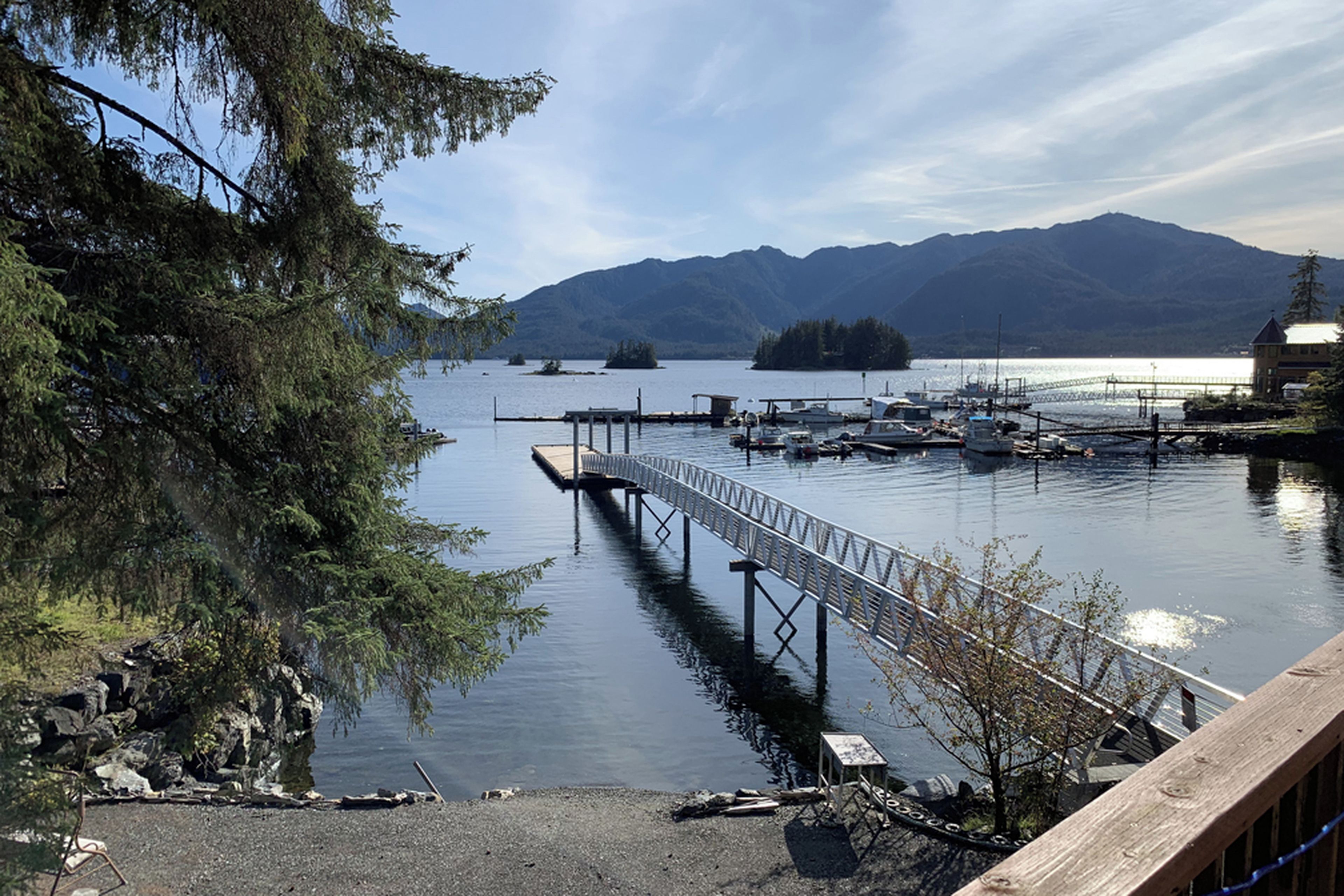 Un lac paisible, avec une jetée qui s’avance sur l’eau, entouré de montagnes et d’arbres.