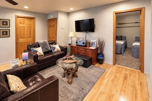 A modern living room with a leather sofa, a glass coffee table, and a flat-screen TV mounted on the wall. - Ketchikan Beach Retreat Dock On-site (Ketchikan)