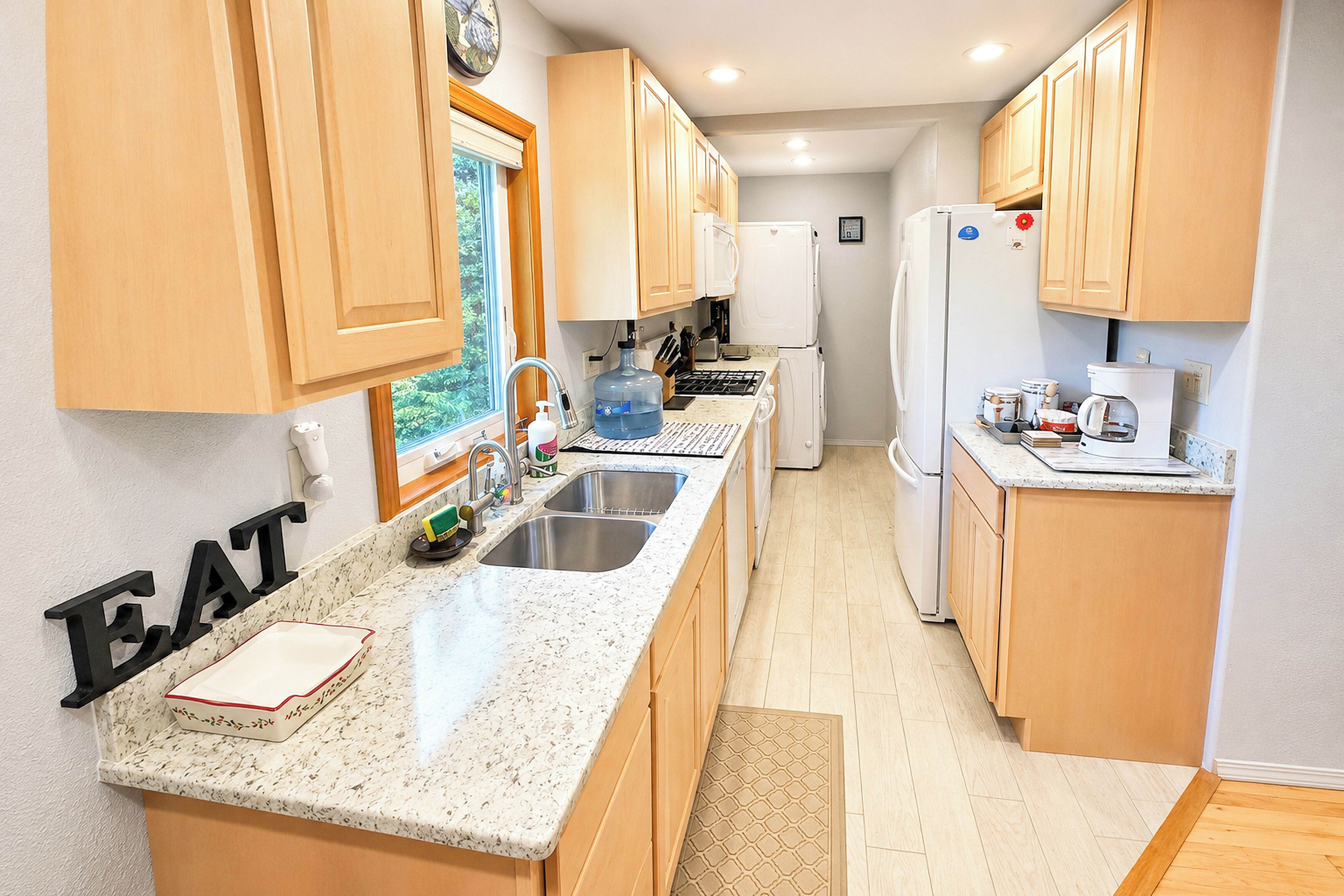 A kitchen with wooden cabinets, a granite countertop, a sink, and a refrigerator.