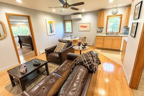 A modern living room with a leather sofa, a coffee table, and a dining area with a table and chairs. - Ketchikan Beach Retreat Dock On-site (Ketchikan)