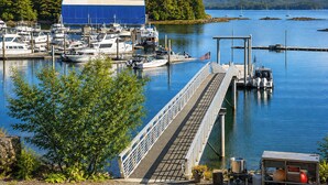 Una marina con imbarcazioni ormeggiate, un molo che si protende nell'acqua e un grande edificio sullo sfondo.