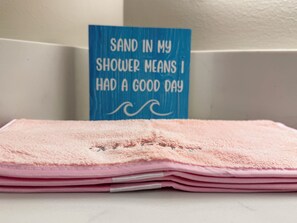 A stack of pink towels with a blue sign in the background. - Salt Life Retreat - Waterfront Getaway in the Heart of Morehead City! (Morehead City)