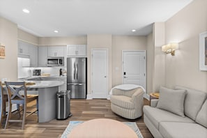 A modern kitchen with stainless steel appliances, a dining area with a coffee bar, and a living room with a sofa and a patterned ottoman. - Salt Life Retreat - Waterfront Getaway in the Heart of Morehead City! (Morehead City)