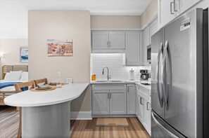 Una cocina moderna con gabinetes grises, un refrigerador de acero inoxidable y una barra desayunadora.