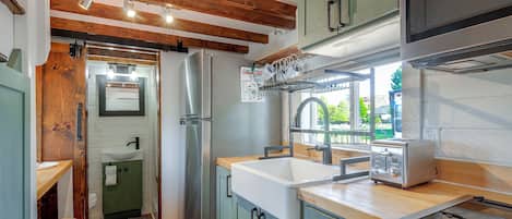 Une cuisine compacte avec des poutres en bois, un réfrigérateur en acier inoxydable, un évier et un grille-pain.