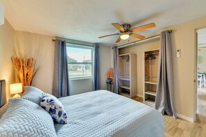 A bedroom with a bed, a ceiling fan, a window with curtains, and a view of the outside. - Canal-front Englewood Cottage Near Beaches (Englewood)
