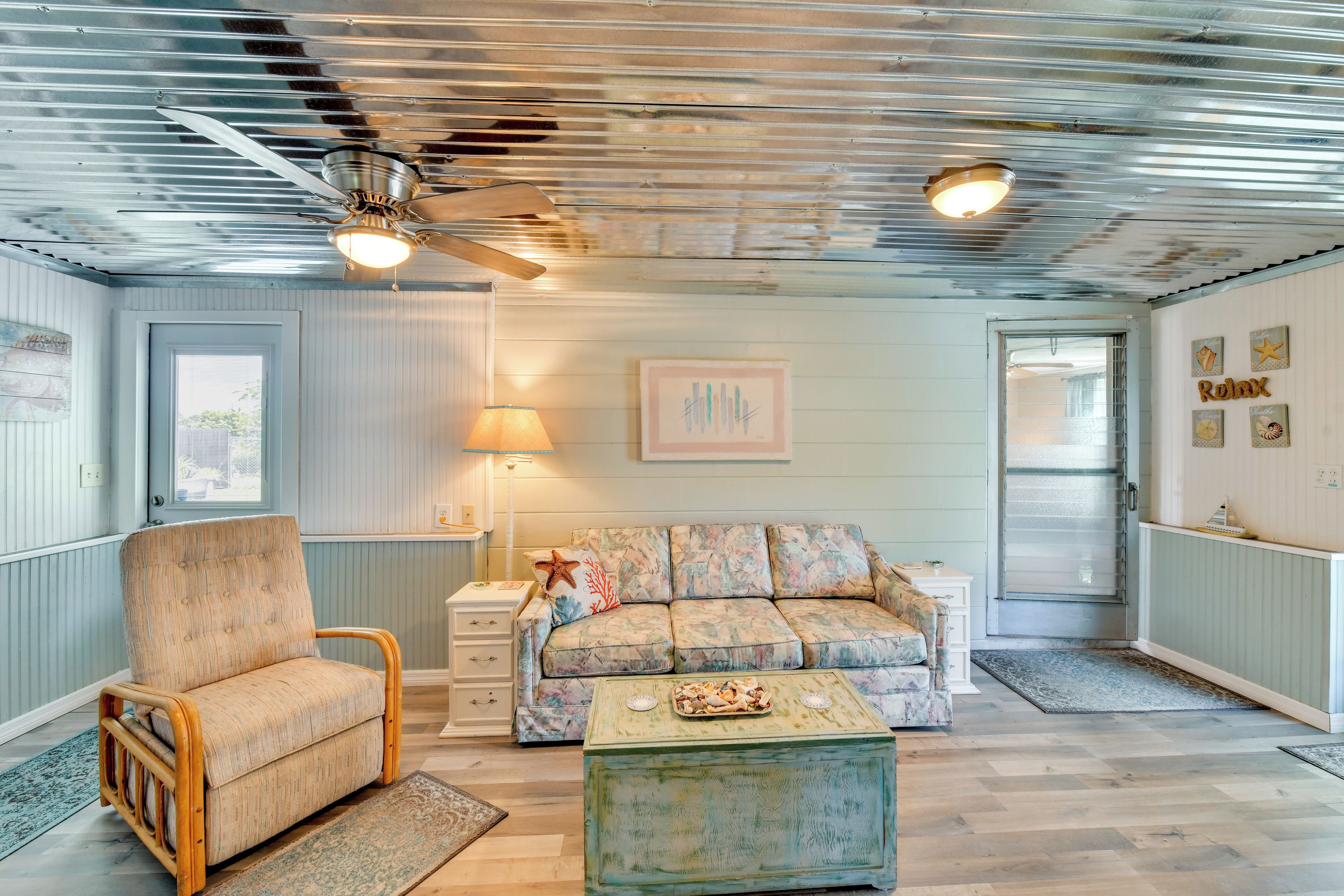 A room with a ceiling fan, a sofa, a chair, a small table, and a lamp.