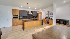 Cocina moderna con una isla central, armarios de madera y un comedor con una mesa grande y sillas.