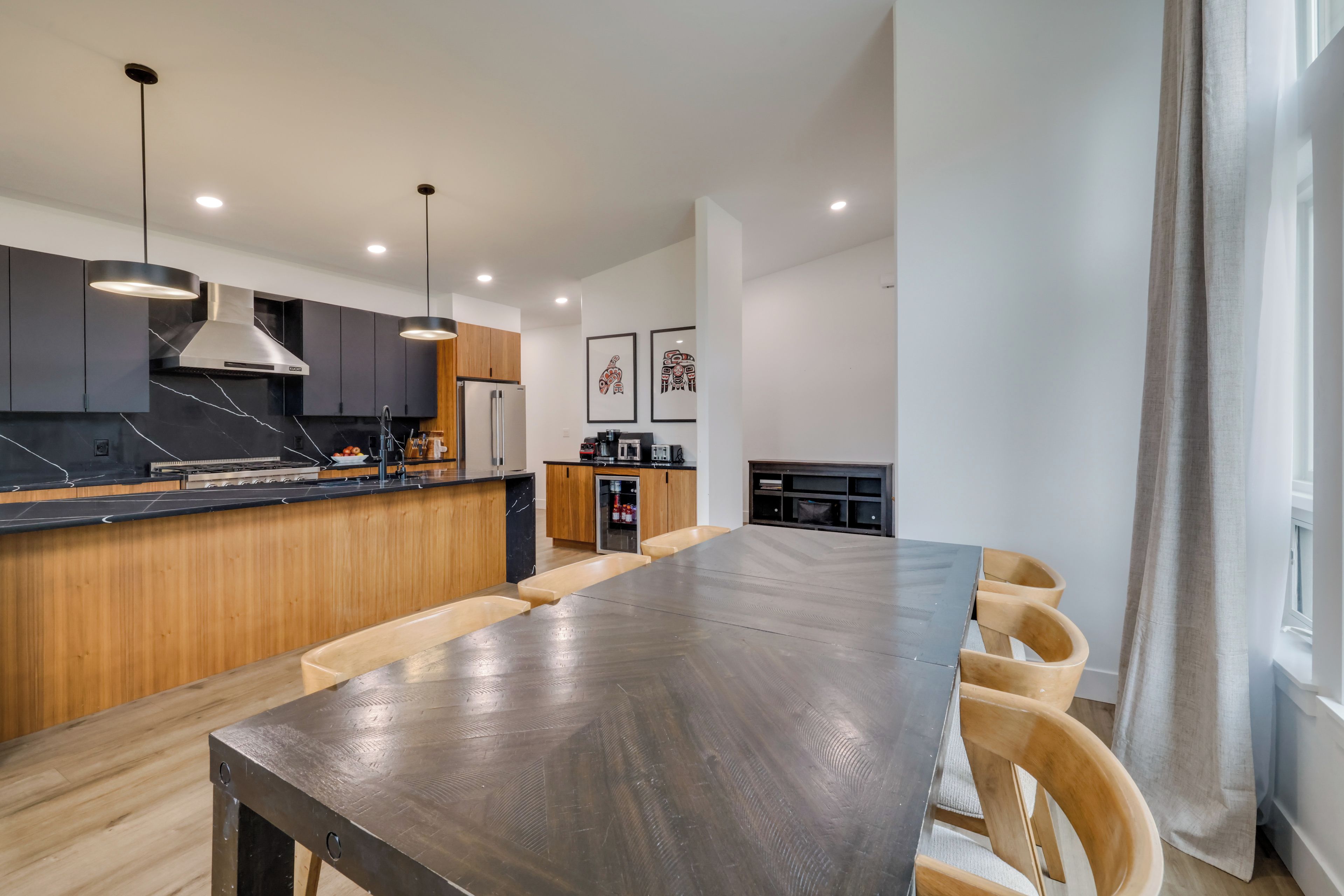 A modern kitchen with a central island, wooden cabinets, and pendant lighting.