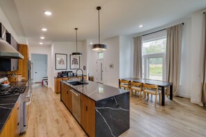 Una cocina moderna con una isla central, armarios de madera, horno empotrado y un comedor con mesa y sillas.