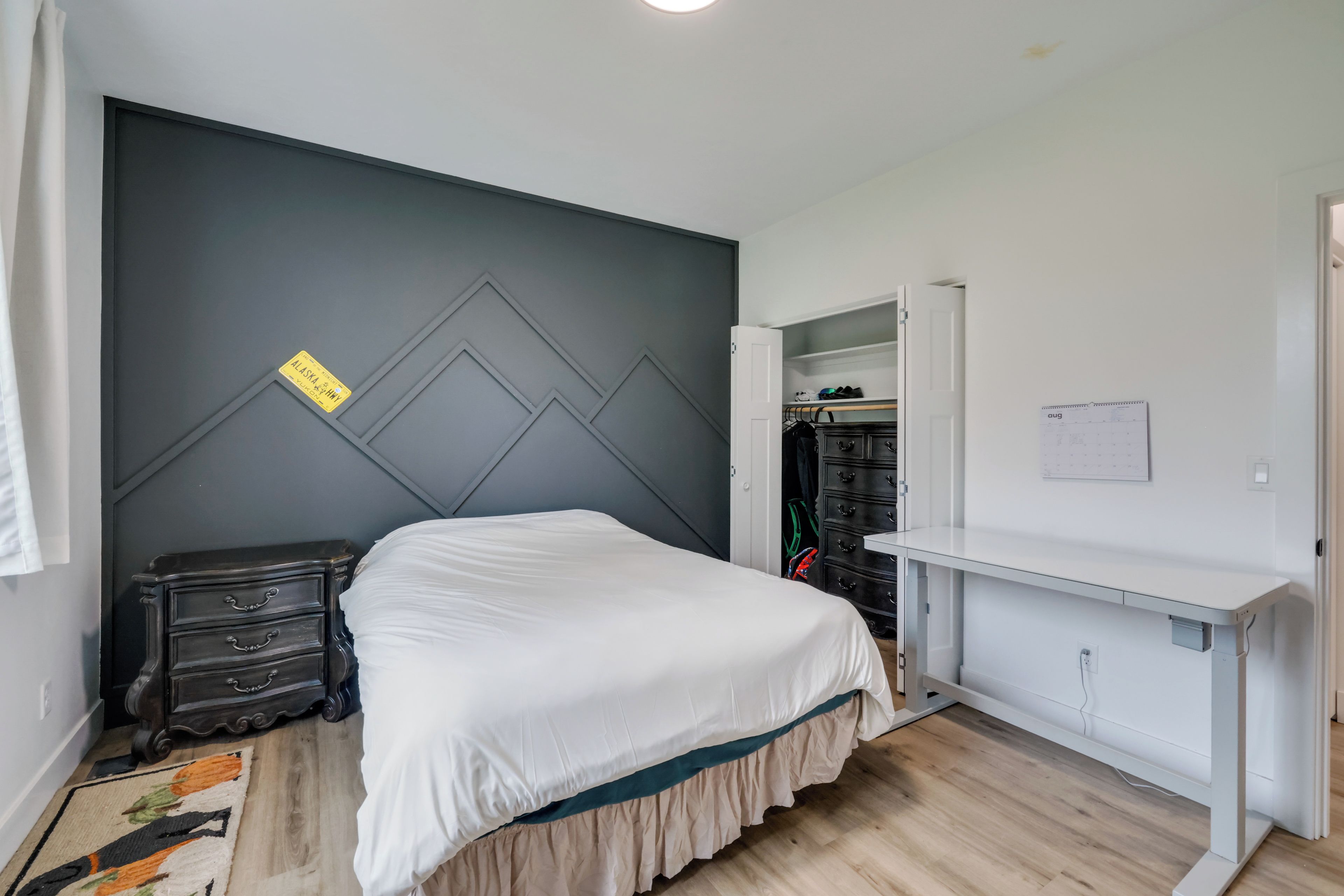 A bedroom with a bed, a dresser, a wardrobe, and a desk.