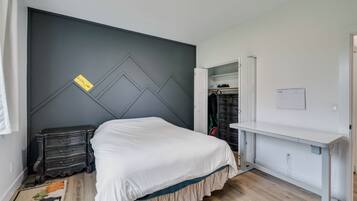 A bedroom with a bed, a dresser, a wardrobe, and a desk.
