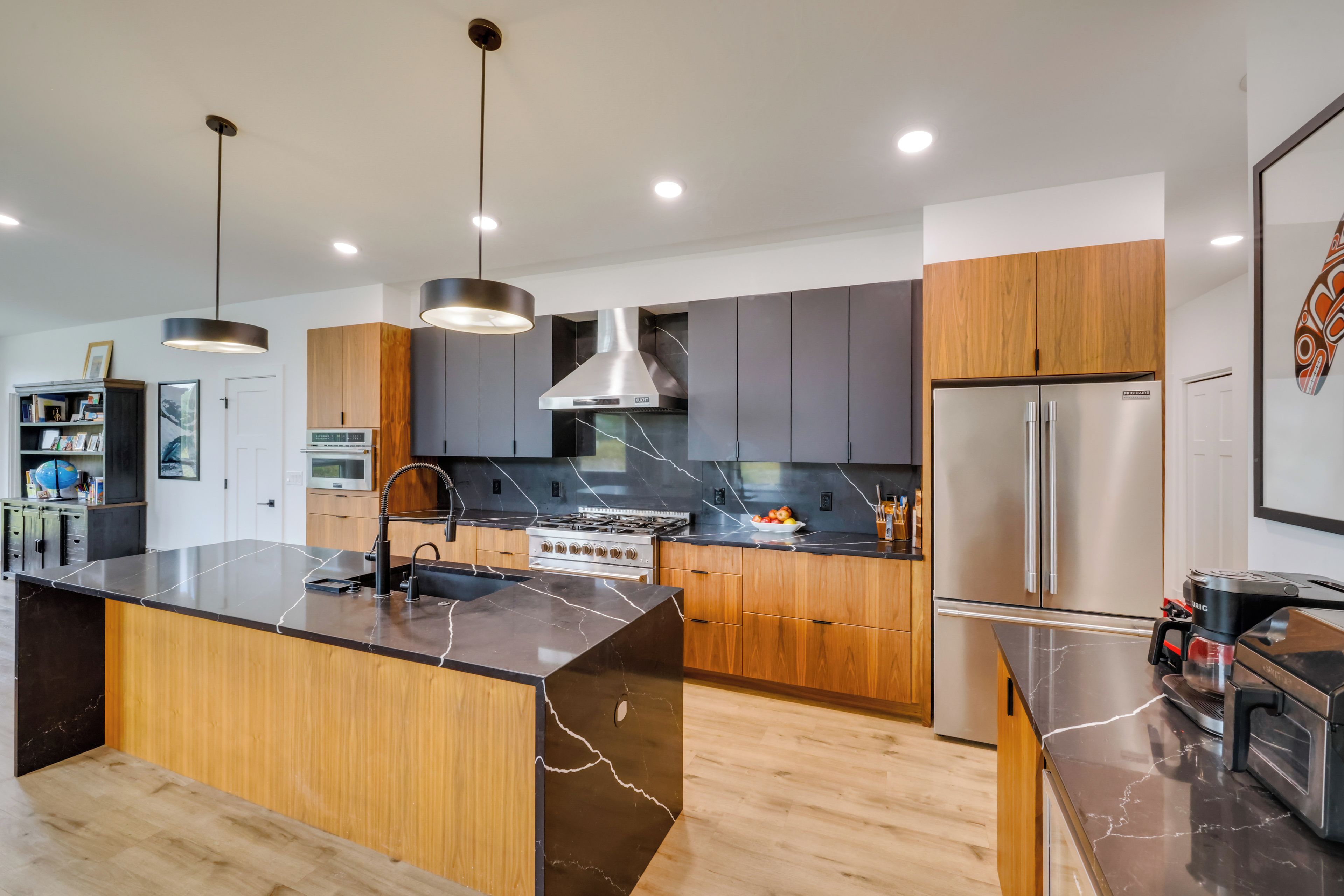 A modern kitchen with a central island, stainless steel appliances, and wooden cabinetry.
