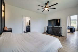 Quarto com cama grande, ventoinha no teto, cômoda e televisão.