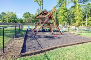 A playground with a wooden swing set and a fenced play area. - Communal Fire Pit & Dock! Tiny Home By Lake Murray (Gilbert)