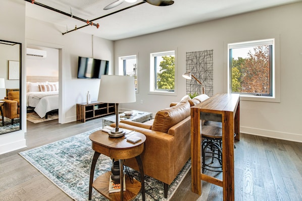 A modern living room with a sofa, coffee table, and a dining area with a wooden table and chairs. - Remodeled Getaway in the Heart of Mountain Home! (Mountain Home)