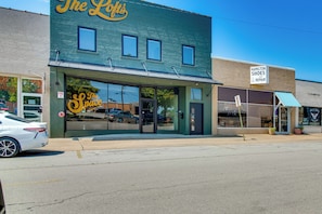 Una fachada con un letrero grande que dice 'The Loft's' y un letrero más pequeño para 'Hamilton Shoes and Repair' al otro lado de la calle.