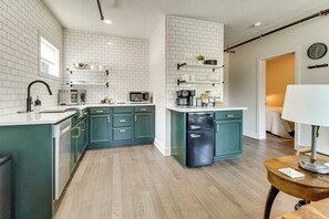 Una cocina moderna con azulejos blancos tipo metro, un microondas integrado y un refrigerador negro.