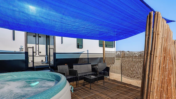 A hot tub area with a blue shade sail, outdoor furniture, and a pool. - Hot Tub, Picnic Area: RV Stay in Carlsbad (Carlsbad)