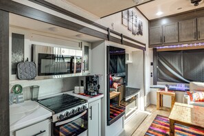 A compact kitchen with a stove, oven, microwave, and a small dining area with a table and chairs.