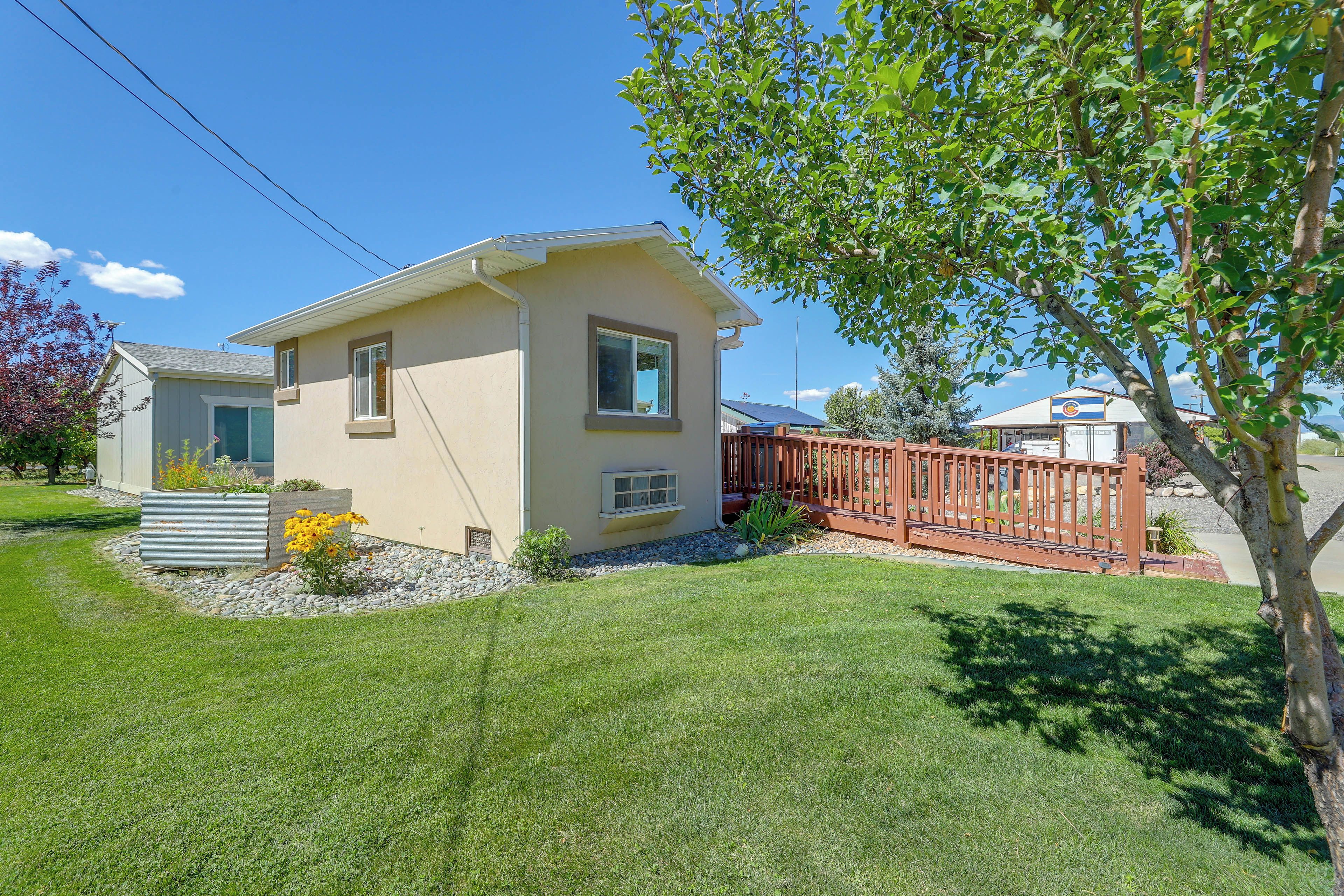 A single-story house with a small front yard, a wooden fence, and a tree.