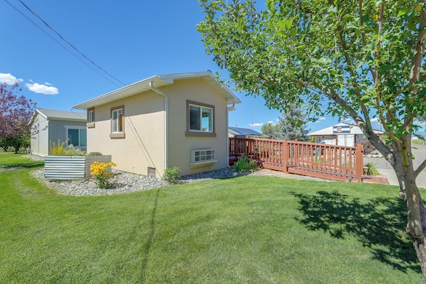 A single-story house with a small front yard, a wooden fence, and a tree.