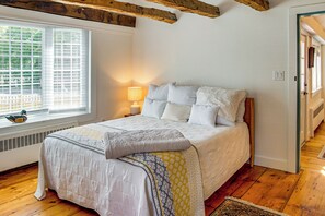 A bedroom with a bed, a window with blinds, a lamp, and a radiator. - Walk to Main St! Osterville Cottage w/ Patio (Osterville)