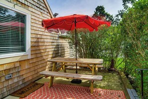 Eine Holzterrasse mit Picknicktisch und einem roten Sonnenschirm.