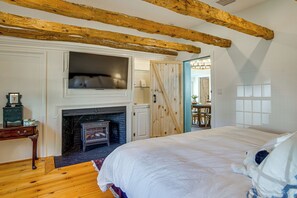 Un dormitorio con chimenea, televisor y cama.