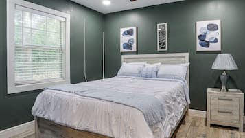A bedroom with a bed, a nightstand, a lamp, and artwork on the walls.