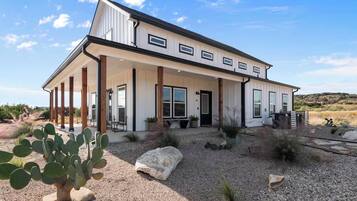 A two-story house with a covered porch, large windows, and a desert landscape.