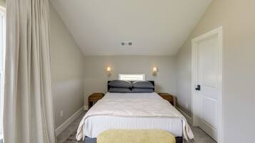 A bedroom with a bed, two bedside tables, a window, a door, and a curtain.