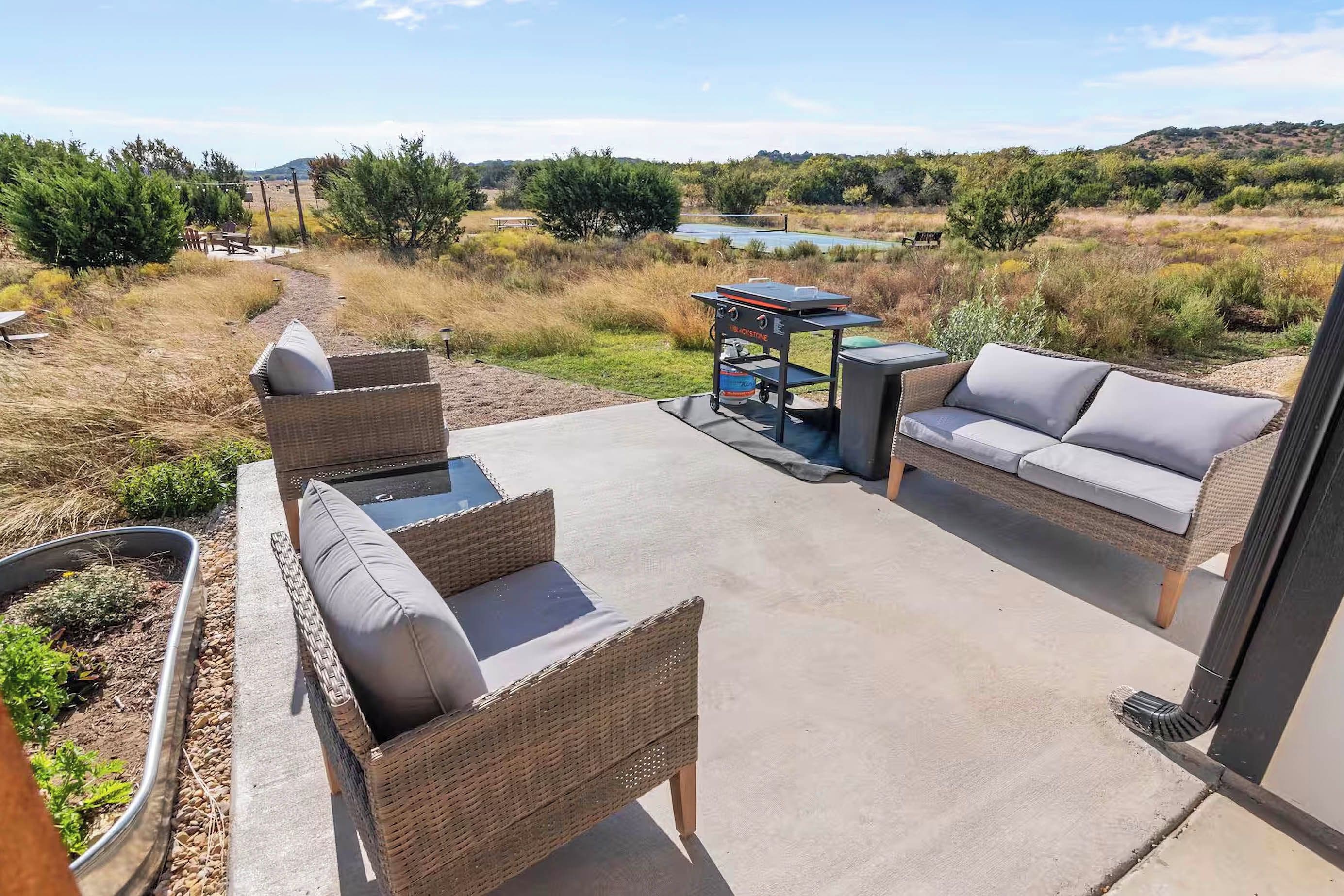 An outdoor patio with wicker furniture and a grill.