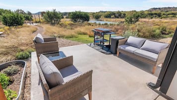 An outdoor patio with wicker furniture and a grill.
