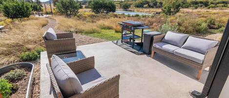 An outdoor patio with wicker furniture and a grill.