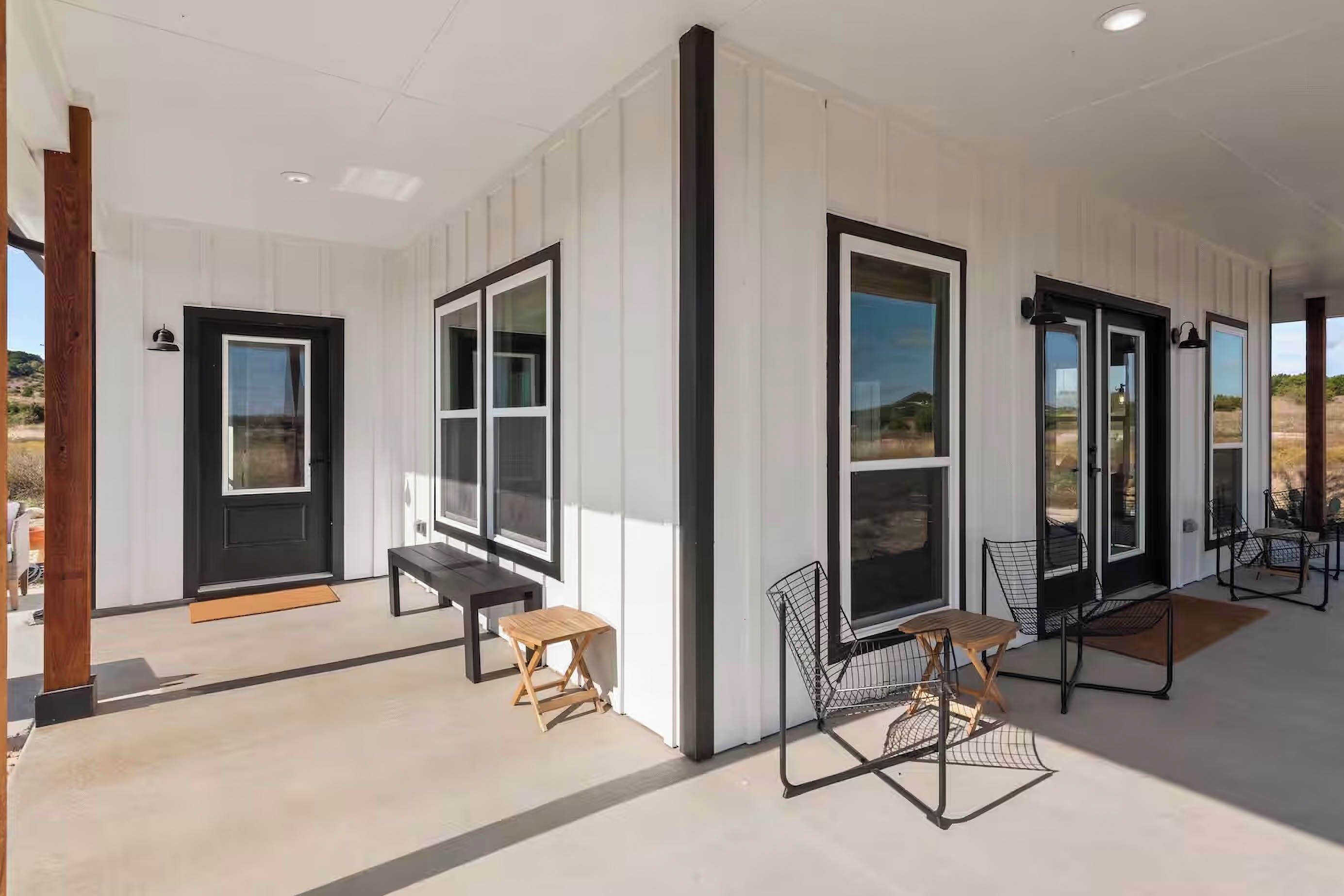 A modern building with large windows, a wooden bench, and a metal chair.