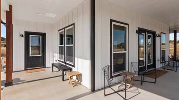 A modern building with large windows, a wooden bench, and a metal chair.