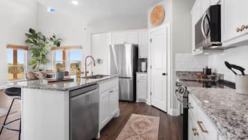 A modern kitchen with white cabinetry, stainless steel appliances, and a granite countertop.