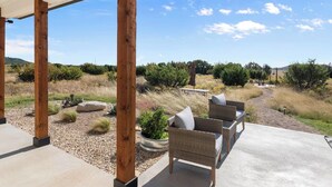 A covered patio with outdoor furniture, a concrete floor, and a view of a natural landscape with shrubs and trees. - Private Pickleball Court! Family Glen Rose Getaway (Glen Rose)
