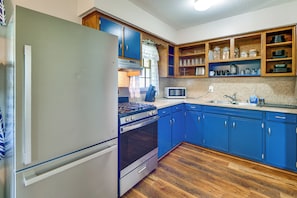 A kitchen with blue cabinets, a stainless steel refrigerator, a microwave, and wooden shelves above the counter. - 2 Mi to Csu, Lake Oliver & Airport! Home w/ Yard (Columbus)