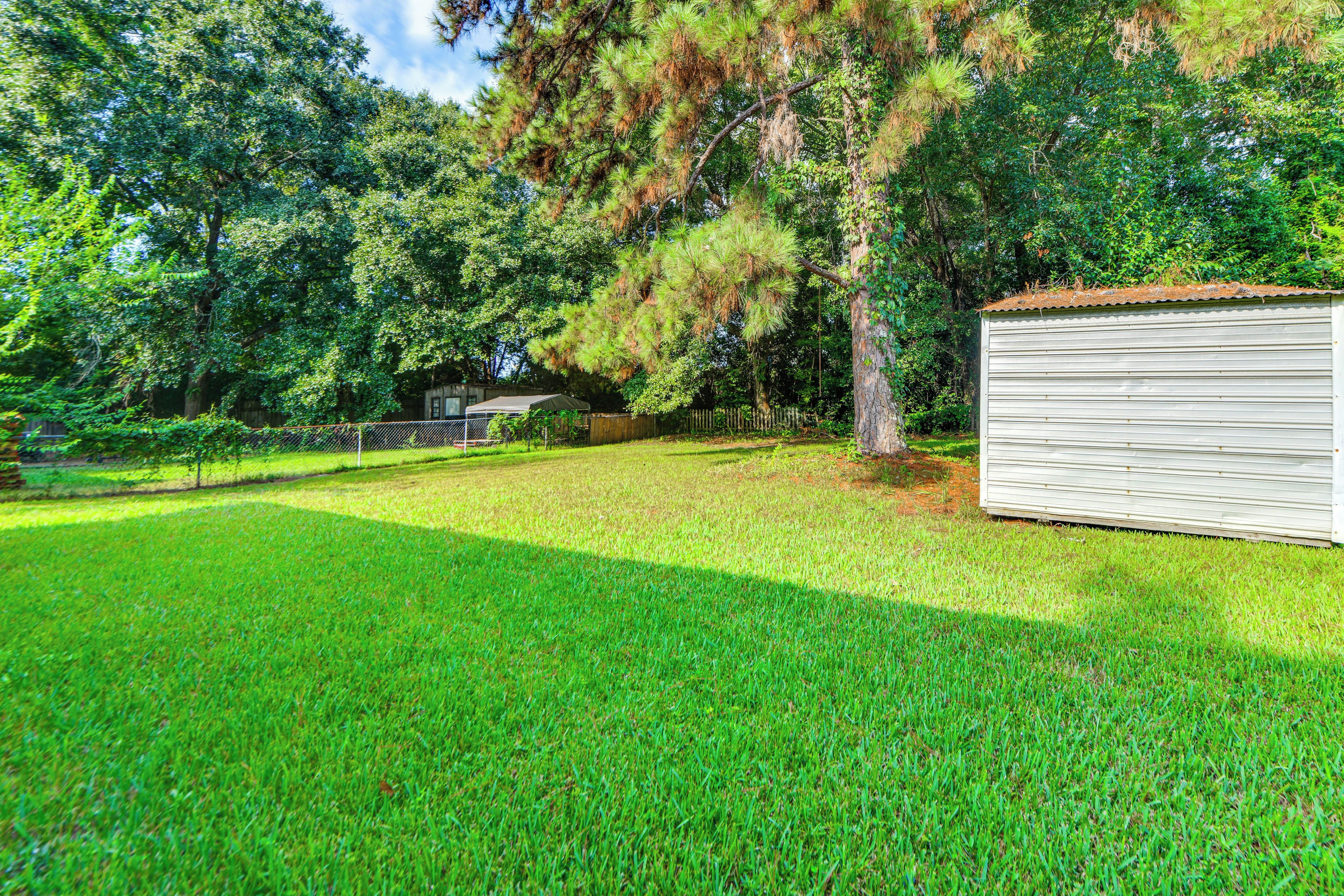 A well-maintained grassy yard with a metal shed and a tree.