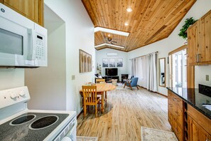 A modern kitchen with wooden cabinets, a built-in microwave, and a dining area with a wooden table and chairs.