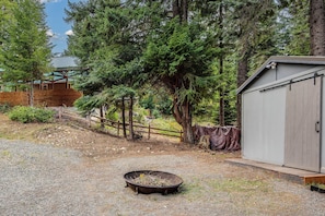 A gravel yard with a metal barrel, a wooden fence, and a shed.