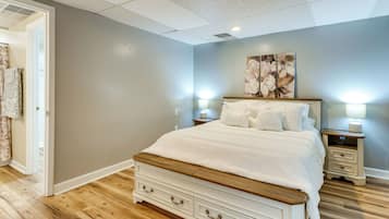 A bedroom with a bed, nightstands, a dresser, and a door leading to a bathroom.