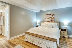 A bedroom with a bed, nightstands, a dresser, and a door leading to a bathroom.